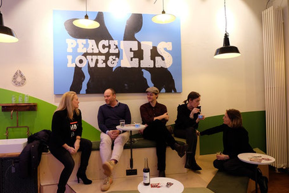 Some people with Ben and Jerrys and poster that says Love, Peace, Eis