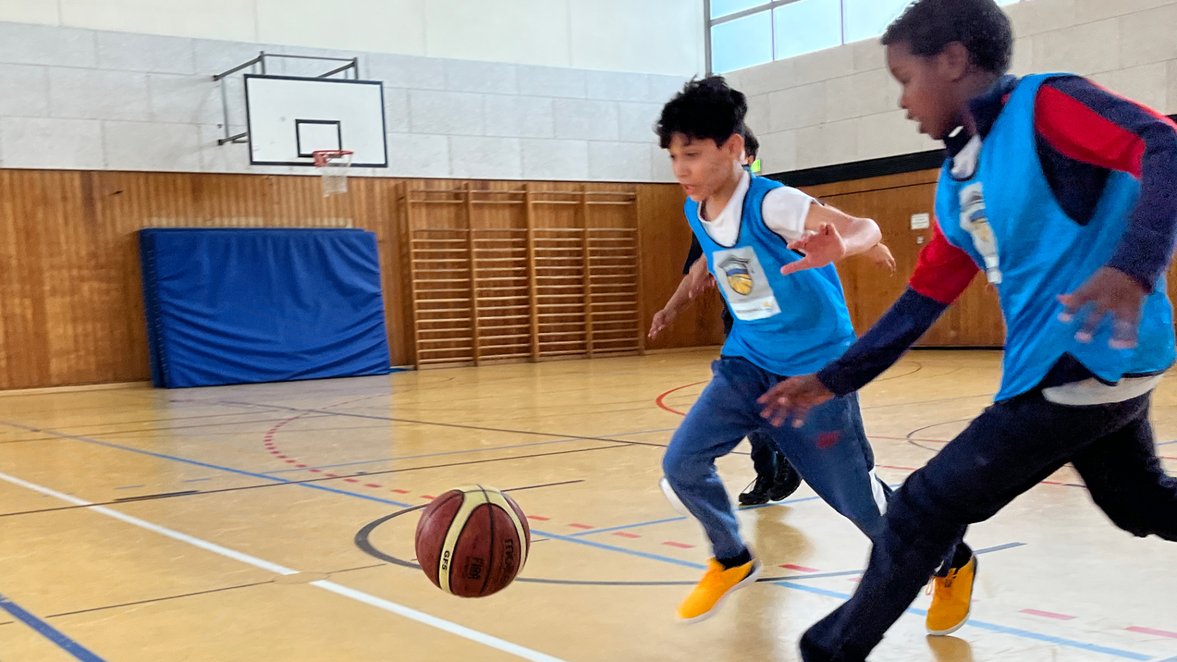 Kinder spielen Basketball in einer Halle